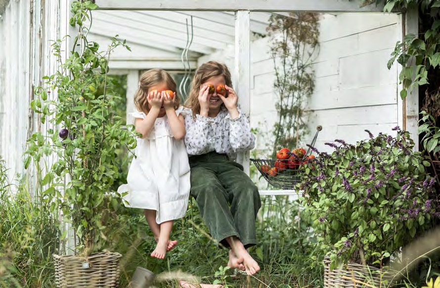 Zwei Mädchen halten sich Tomaten vor die Augen